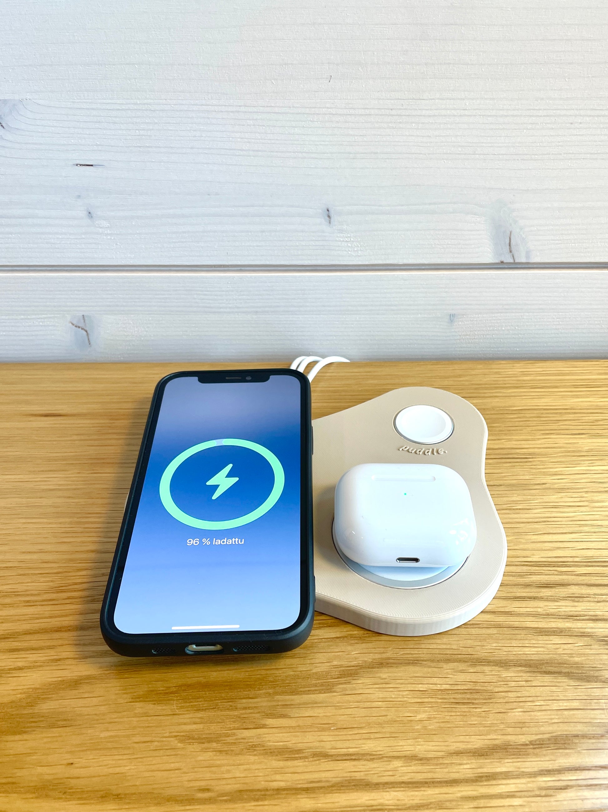 Beige Puddle III MagSafe latausteline lataamassa iPhonea ja AirPod-koteloa