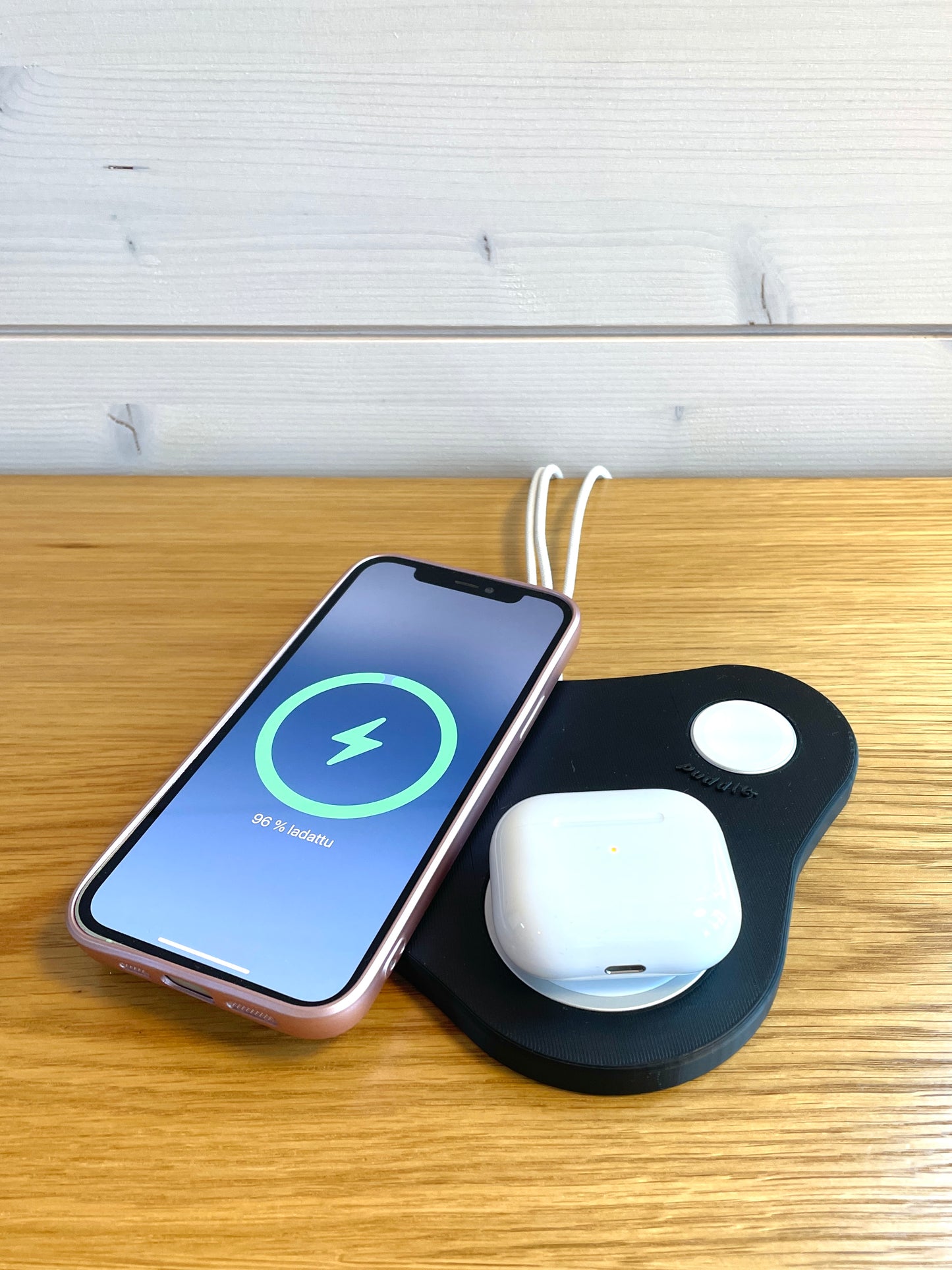 Musta Puddle III MagSafe latausasema lataamassa AirPod-koteloa ja iPhonea