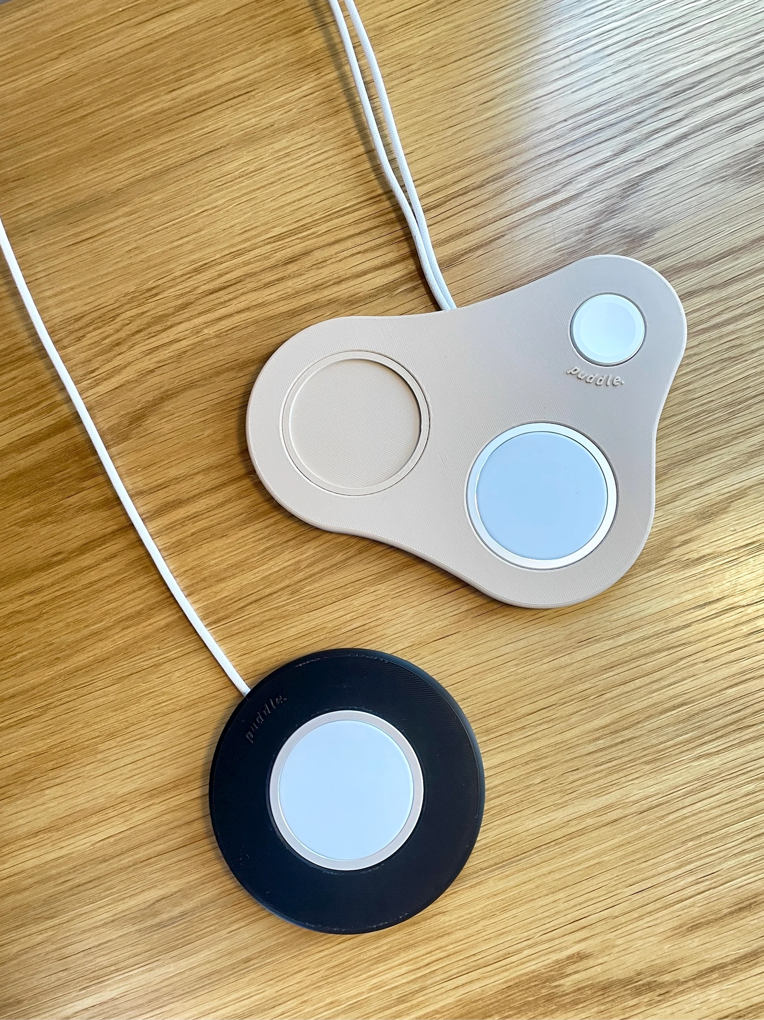 Musta Puddle kännykkäteline iPhonelle ja beige MagSafe laturinteline iPhonelle, AirPod-kotelolle sekä Apple Watchille